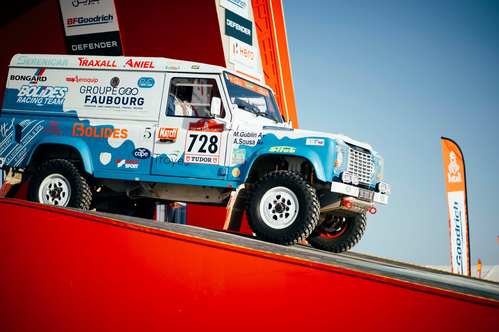 Blau-weißer Land Rover Defender auf roter Rampe