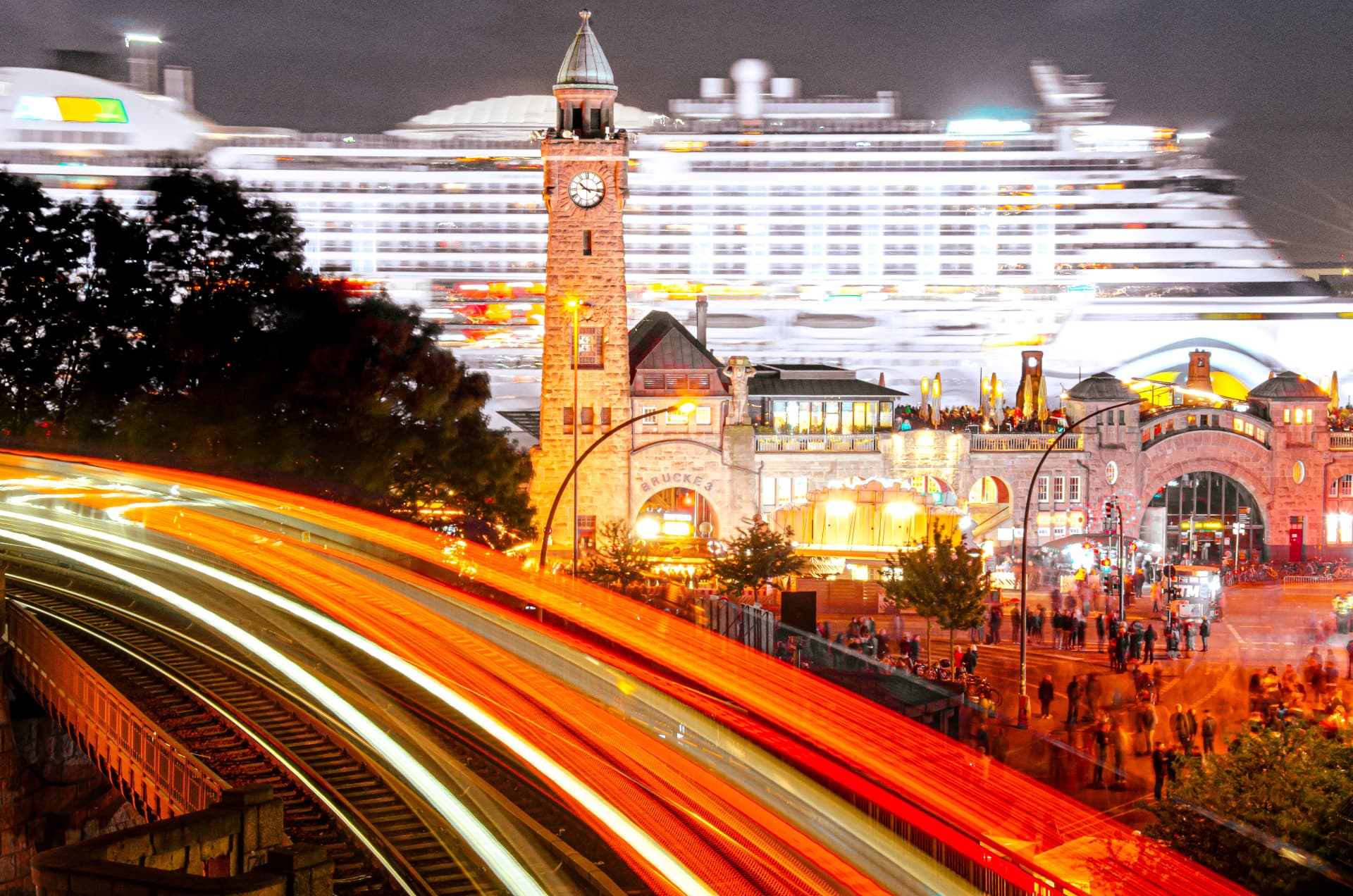 Landungsbrücken bei Nacht mit Lichtspuren und Kreuzfahrtschiff