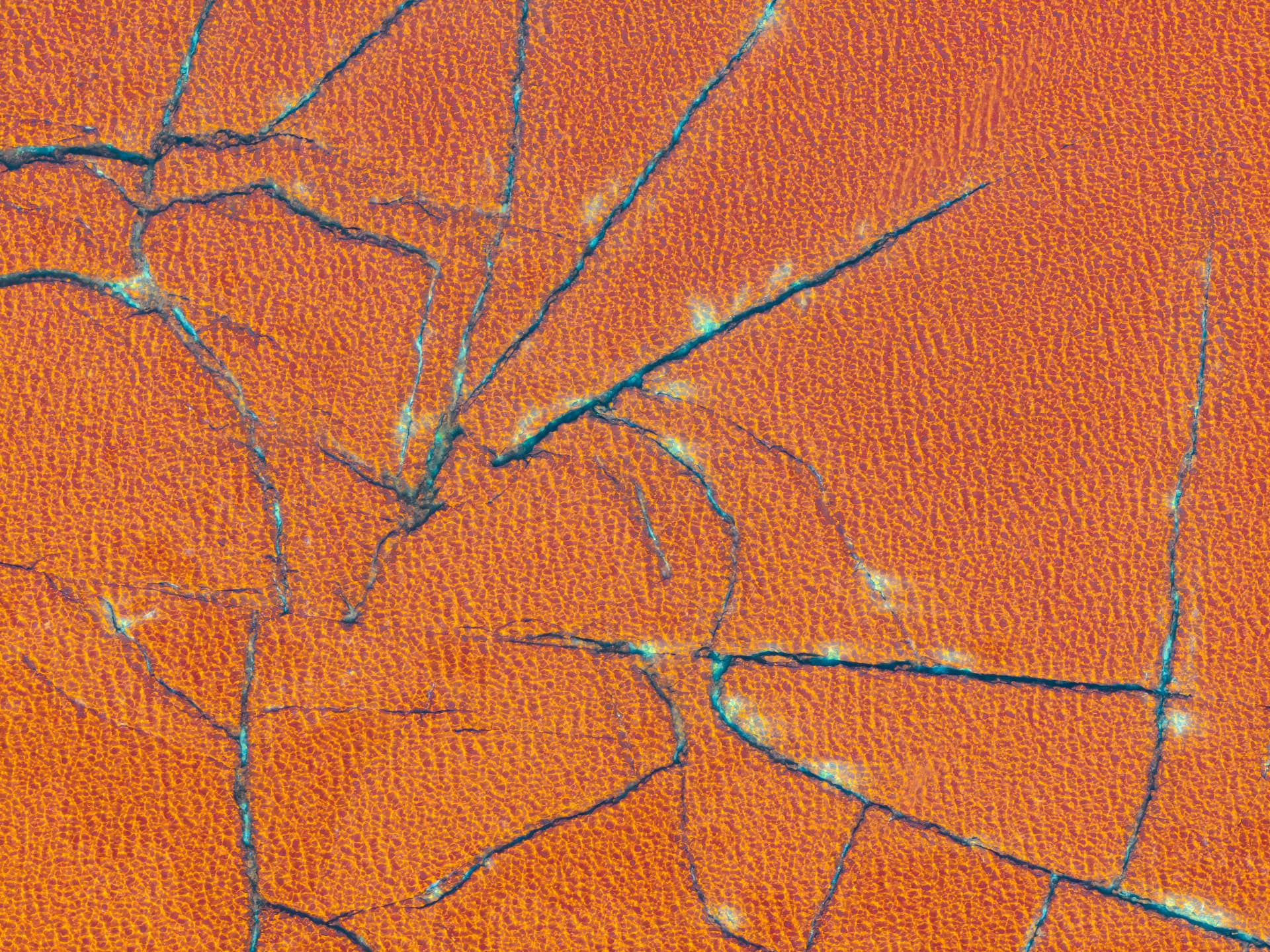 Luftaufnahme einer orangen Salzfläche mit Rissen