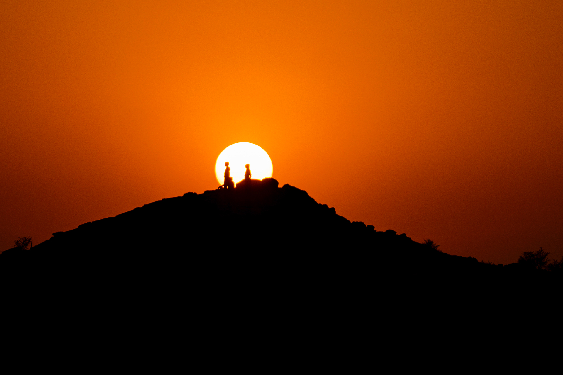 Sonnenuntergang über einem Wüstenkamm mit Silhouetten am Horizont
