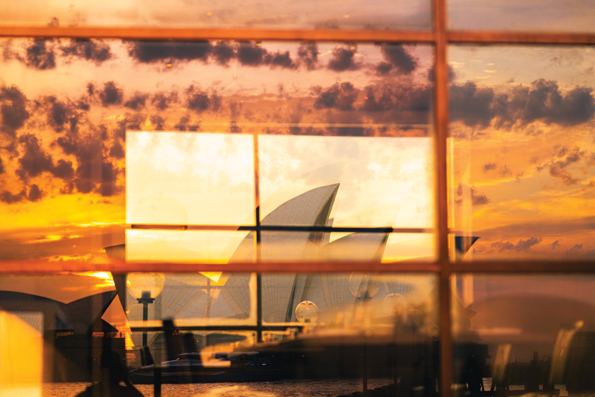 Spiegelung des Sydney Opera House in einer Fensterfront bei Sonnenuntergang